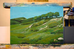 Painting of a grassy hillside, with some rocks about, and trees on top right.
